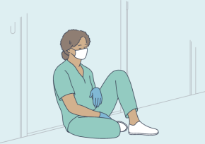 A nurse sitting on the floor looking tired